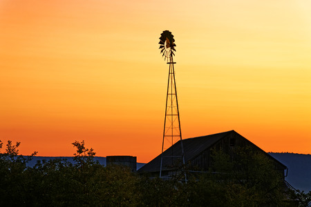 A beautiful sunrise on a rustic Amish barn with a windmill in Pennsylvania, USA.の写真素材