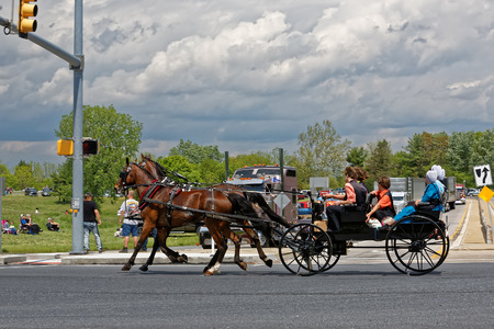 LANCASTER PA - MAY 14 2017: An Amish carriage passes the Make-A-Wish Foundation truck convoy. On the Mother's Day annual fundraiser truckers grant a Lancaster County wish ride to children with life-threatening illnesses.のeditorial素材