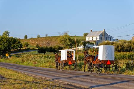 MILROY PENNSYLVANIA - September 4, 2016: Amish families travel with horse and carriage on a winding rural road in Mifflin County, Pennsylvania.のeditorial素材