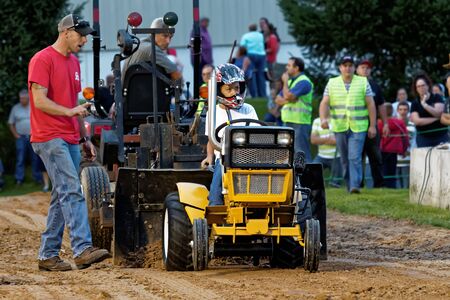 MYERSTOWN, PENNSYLVANIA - SEPTEMBER 14, 2018: A young girl drives a modified lawn tractor at Myerstown East End Days. The tractor pull is an annual community event.のeditorial素材