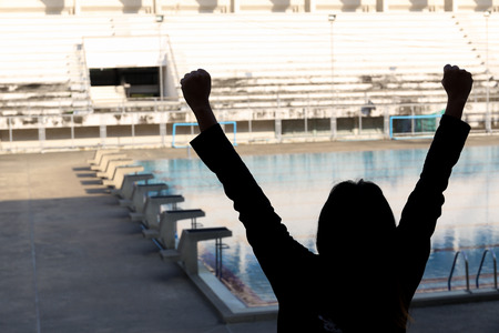 silhouette person raise two hands to celebrate with empty swimming pool backgroundの写真素材