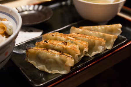 Fried Gyoza or Japanese dumpling on black disk in Japanese restuarantの写真素材