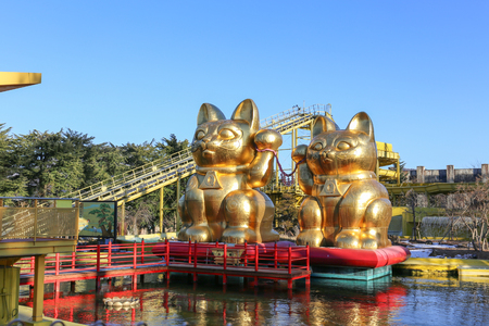 YAMANASHI, JAPAN - FEBRUARY 15: There are golden cat statues name "Maneki Neko" near Nagashimasuka playing machine in Fuji-Q Highland amusement park February 15, 2017 in Tokyo, Japanのeditorial素材