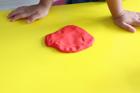 kid pressed red play dough on yellow tableの写真素材