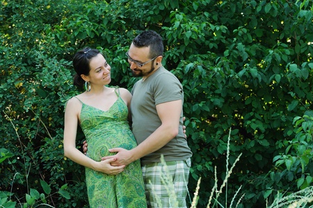 Happy couple future parents outside in the park.