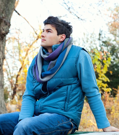 Young stylish man sitting in autumn park.の写真素材