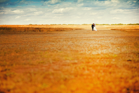 Bride and groom walking in autumn field outdoor.の写真素材