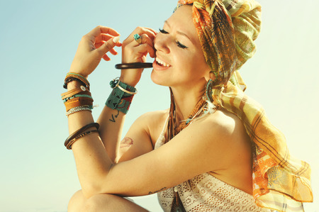 African style fashion woman portrait with headband and handmade necklace and earrings, sunny backlit outdoor photo, boho chic styleの写真素材