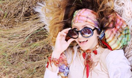Dressed in boho chic style woman portrait lying on a hay and fur, close up, healthy and happy concept, autumn outdoor, with copy space for textの写真素材