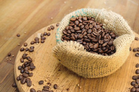 Coffee beans in burlap sack on old wooden backgroundの写真素材