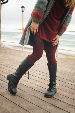 Slim female legs dressed in knee high boots with shoelaces and knitted stockings, outdoorの写真素材