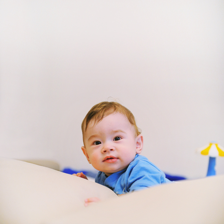 Beautiful infant baby boy lie on a stomach and looking at camera