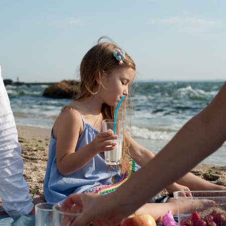 Happy family picnic near sea, little girl drink milk drink milkの写真素材
