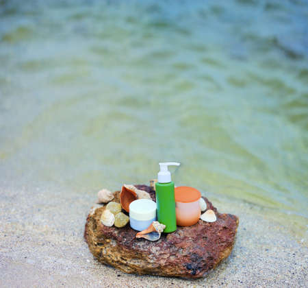 Bath, care and sunscreen cosmetics standing on a stone in sea water