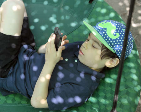 Boy kid with phone at the backyard, summer holidays leisureの写真素材