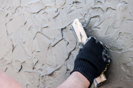 Professional builder moulding decorative texture of venetian plastering on wall with plaster, no faceの写真素材