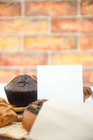 Bright pastries photo mockup with white empty list template and muffin in city cafeの写真素材