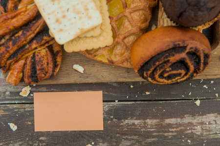 Assorted pasrties set with empty business card on a wooden old style rustic backdrop, flat lay view