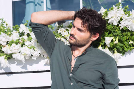 Sexy man model dressed in green shirt, outdoor photo