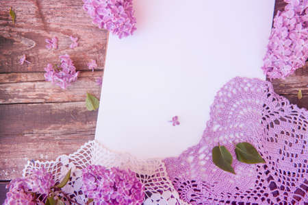 Empty space white list with lilac bunch flowers, wooden backdrop, flat lay top viewの写真素材