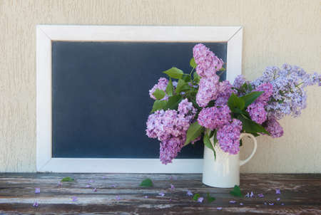 Empty space chalk blackboard with white frame and lilac flowers bouquet, copy space chalkboardの写真素材