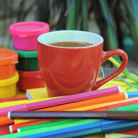 Red tea empty space mug mockup, outdoor photo on art working dekstop with colored felt pensの写真素材