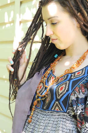 Upset young woman profile portrait looking at her dreadlocksの写真素材