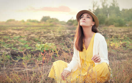 Beautiful young sad woman portrait against sunset autumn field, outdoor, seasonal depressionの写真素材