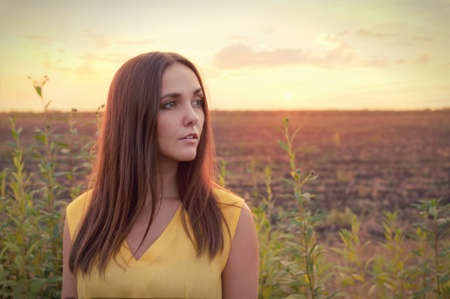 Beautiful young woman portrait against sunset evening field, woman relaxing getaway, outdoor harmonyの写真素材