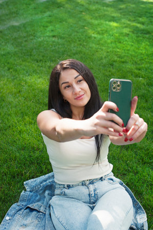 Beautiful young woman outdoor portrait, young woman resting in city park and take a selfie photoの写真素材