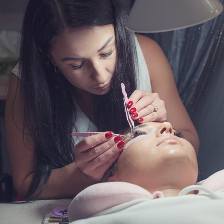 Woman master in salon making eyelash extension to clientの写真素材