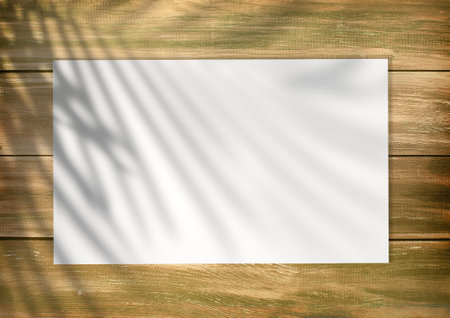 Empty white list on an old style wooden empty background with plam leaf shadow on it. Empty paper mockup, top viewの写真素材