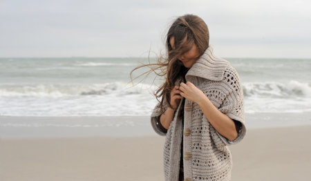 Young brunette woman portrait dressed knitted sweater, hiking near the ocean, windy weatherの写真素材