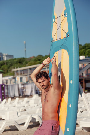 Young surfer man outdoor portrait posing near a surfboardの写真素材