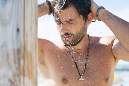 Handsome man taking a shower on the sea beachの写真素材
