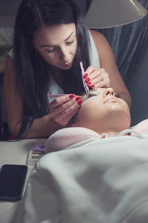 Lash maker master making eyelash extension under lamp light, real procedureの写真素材