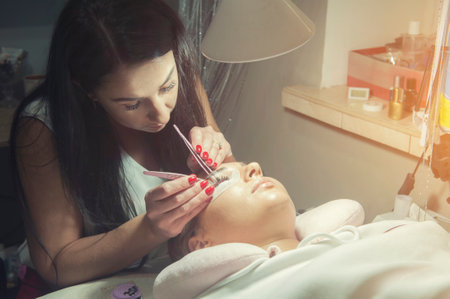 Lash maker master in salon making eyelash extension to client, real procedureの写真素材
