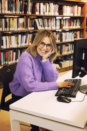 Young beautiful woman librarian working in a city library