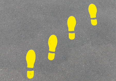 Yellow footprint or foot steps on gray asphaltの写真素材