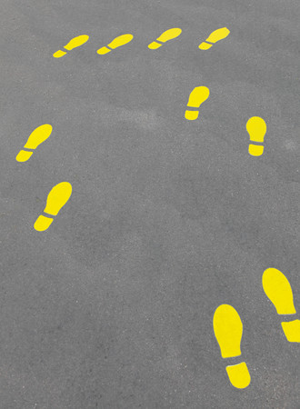 Yellow footprint or foot steps on gray asphaltの写真素材