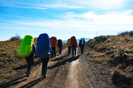 Group of travelers with backpacks on the roadの写真素材