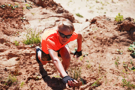 Young blonde man climbing natural sand cliff