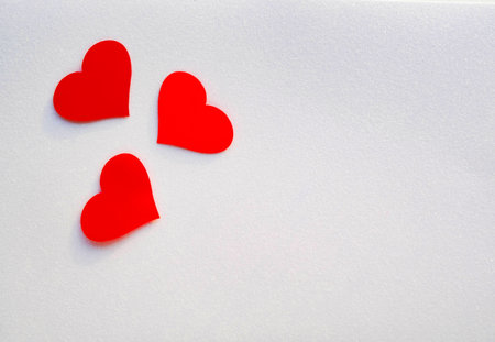 Three red decorative hearts on a glittering white background with copy space. Valentines Day card