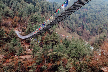 TTrekker crossing metal suspension bridge in Nepal, Himalayas.の写真素材