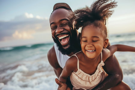 Happy afro american father and daughter having fun together on the beach.の素材
