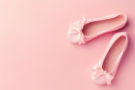 A pair of delicate pastel pink ballet flats with bows on a matching pink backgroundの素材