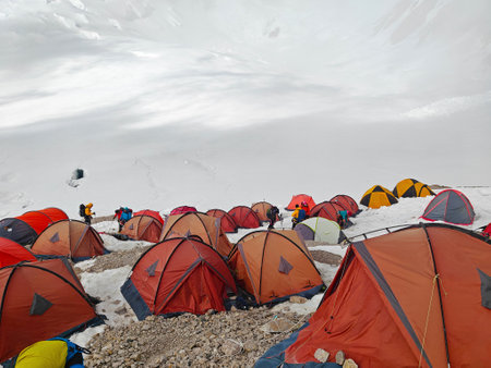 Climbers pitch colorful tents at a snowy site, gearing up for a tough mountain ascent.の写真素材
