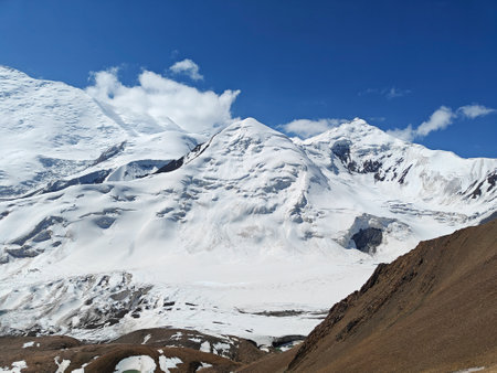 Snow-capped peaks stretch majestically against the bright blue sky in a remote mountainous area...
