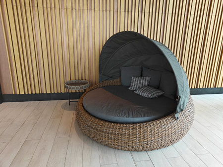 Outdoor lounge chair features a protective canopy and soft cushions, set against a stylish wooden...