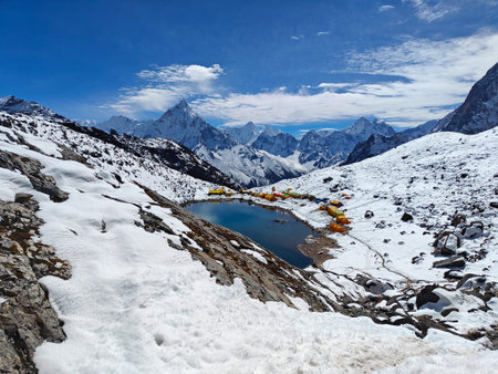 Majestic snowy mountains with tranquil lake and vibrant tents in breathtaking landscape. Himalayan Mountains, Nepalの写真素材